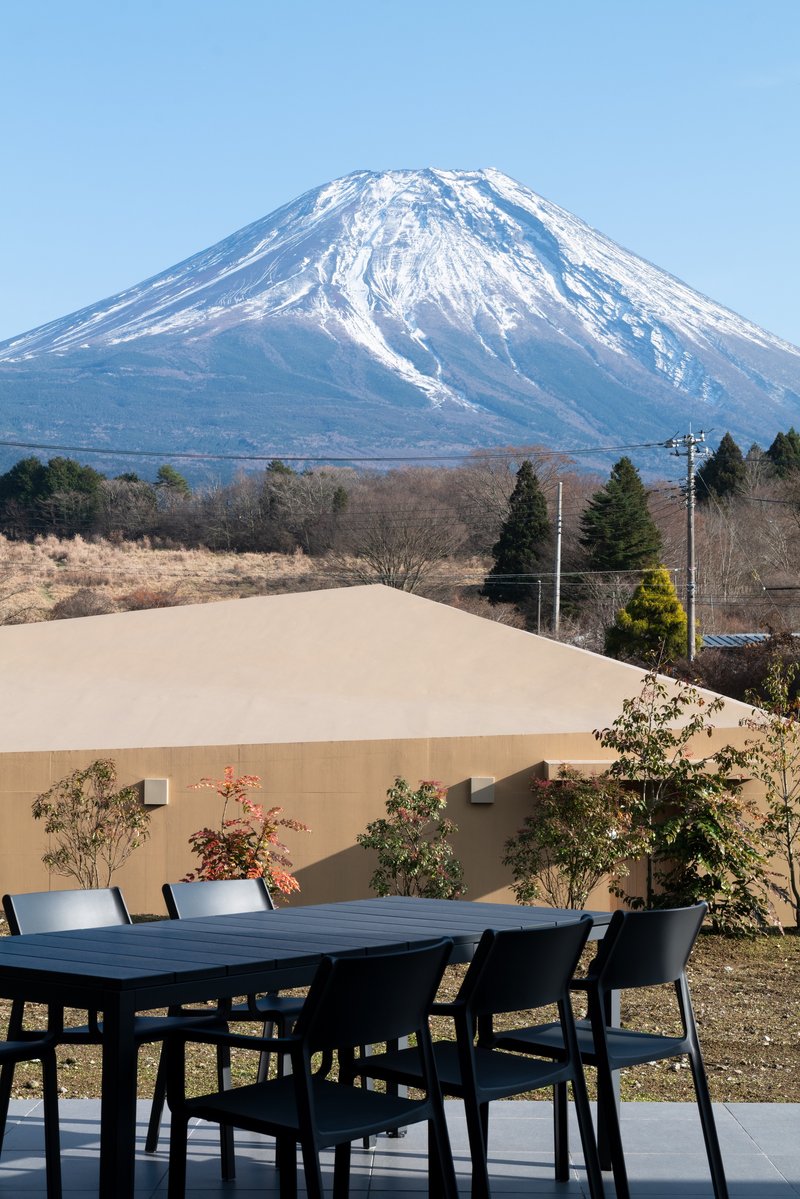Outdoor dining terrace with snowcapped volcanic peak visible beyond the stucco privacy wall