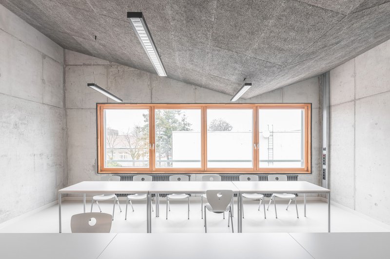 Classroom with paired tables and chairs facing a continuous window with radiators below the sill