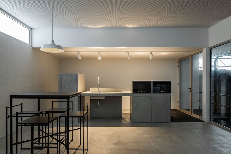 Minimal industrial canteen with clean lines and integrated kitchen core