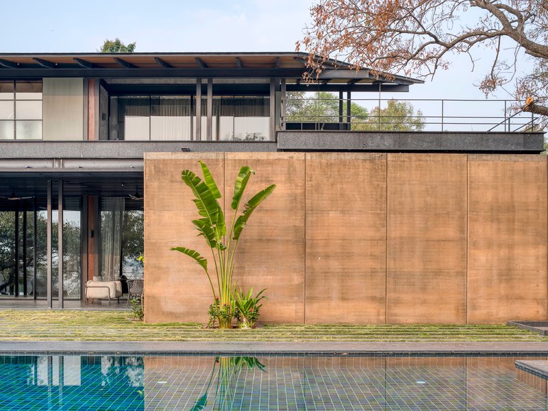 Poolside view of the rammed earth wall with planted banana palms beside the lower terrace