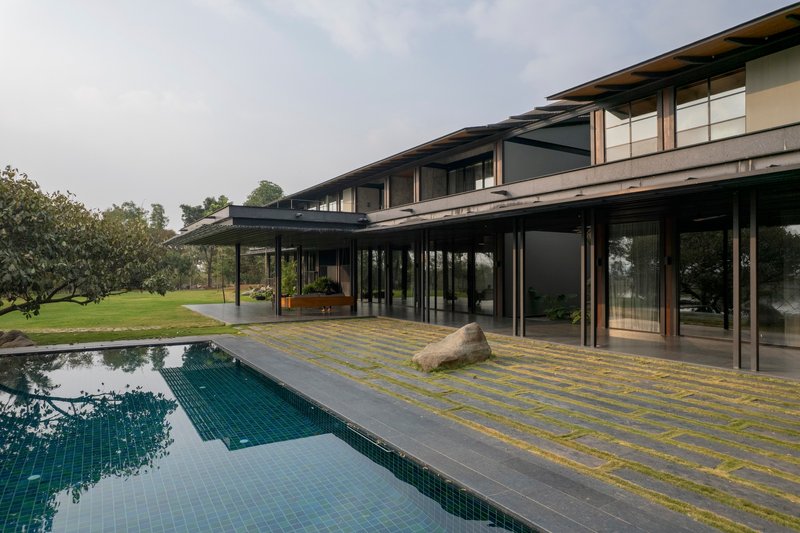 Covered outdoor terrace with steel columns extending along the pool deck and tiled mosaic paving