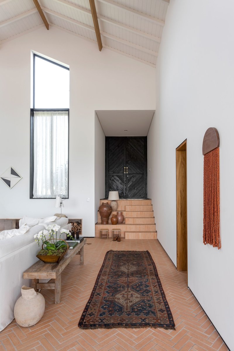 Entry hall with herringbone terracotta floor and exposed timber rafters beneath a vaulted ceiling