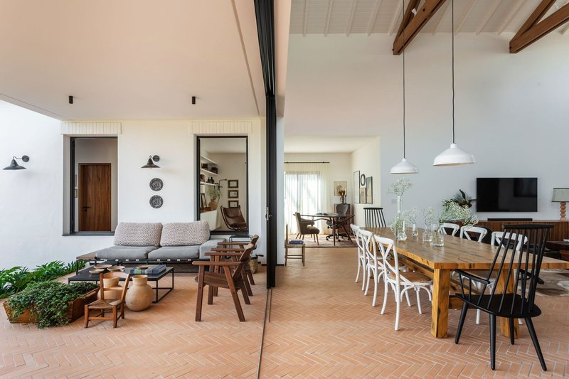 Open-plan living and dining space with herringbone terracotta flooring and exposed timber roof beams