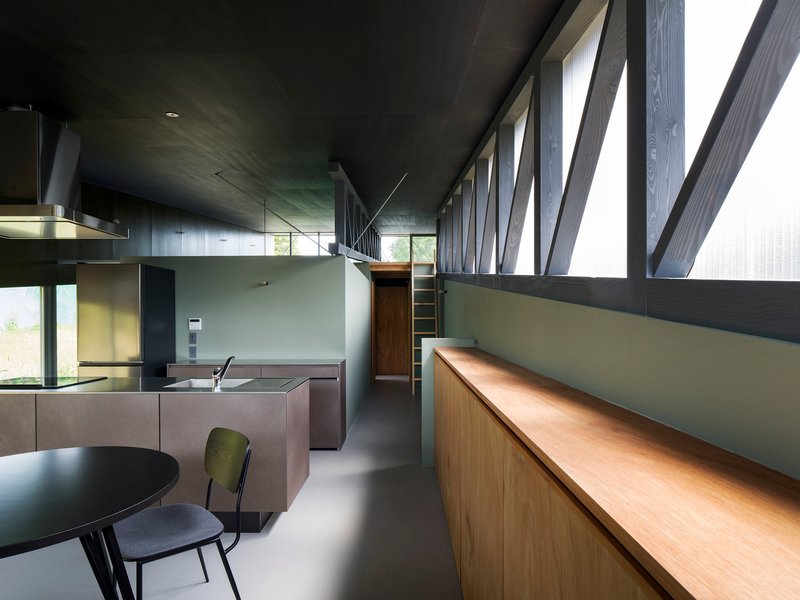 Open kitchen and dining area with diagonal timber bracing visible through translucent upper windows