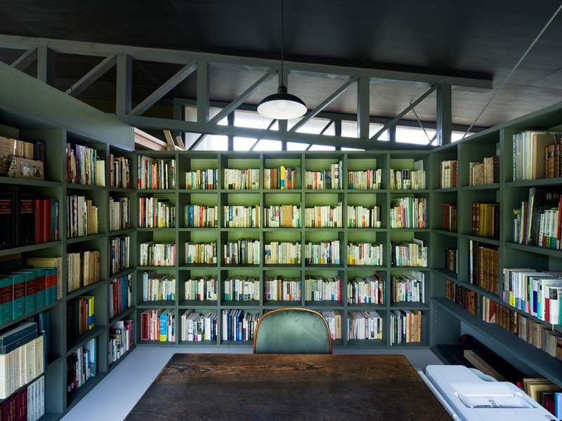 Library with floor-to-ceiling bookshelves and diagonal braced glazing above under concrete ceiling