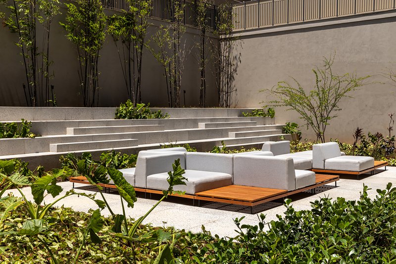 Tiered concrete seating steps with integrated planters and bamboo against a charcoal wall