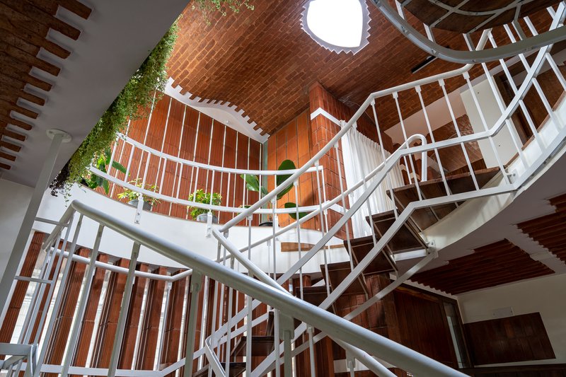 Looking up at the spiral staircase wrapped with vertical planters along the vaulted brick barrel ceiling