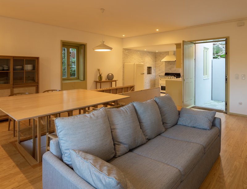Open living and dining area with timber table and grey sofa under warm lighting