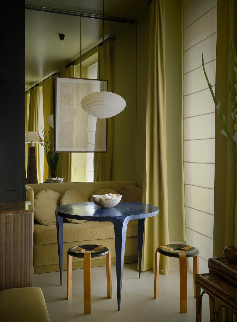 Seating corner with a round blue table, two bentwood stools, and a paper pendant light