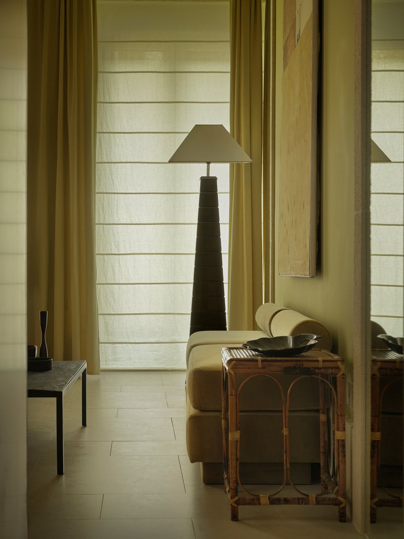 Reading nook with horizontal white timber cladding, yellow curtains, and a tapered pyramidal lamp