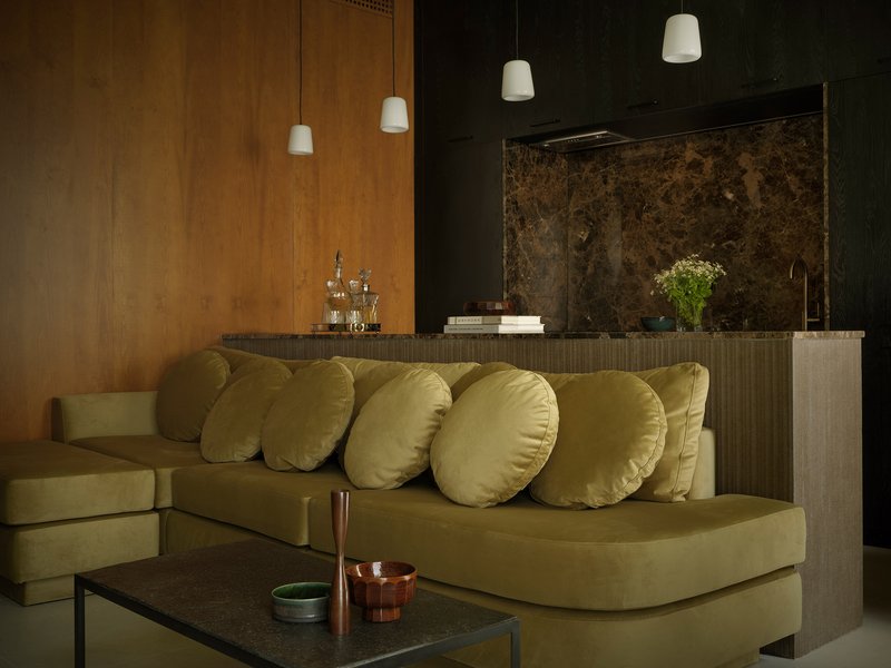 Open living space with a ribbed island, dark marble backsplash, and olive velvet seating