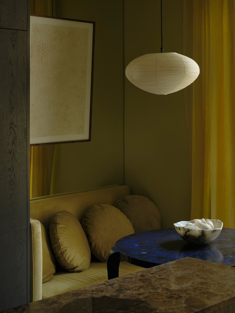 Dining nook with upholstered bench seating, olive paneled walls, and a pendant light fixture