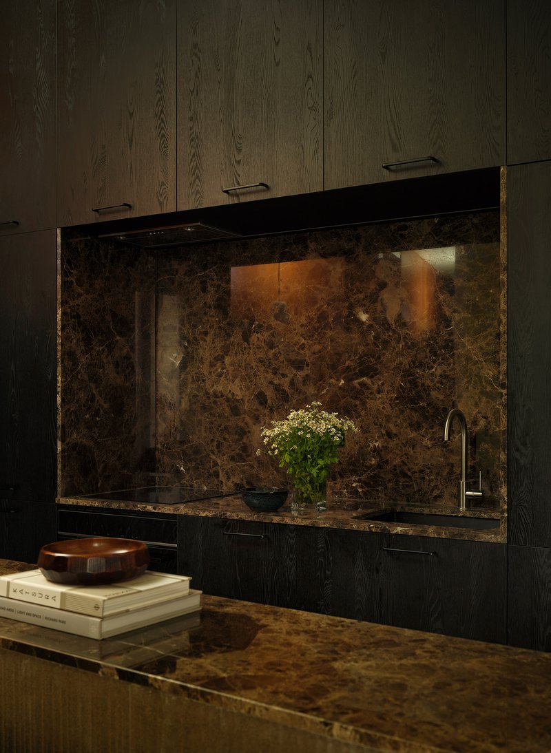 Kitchen counter with dark marble backsplash and base cabinets beneath oak paneled walls