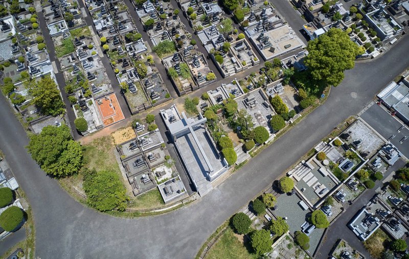 Drone perspective showing the memorial's linear axis aligned with surrounding burial plots and asphalt pathways between green plantings
