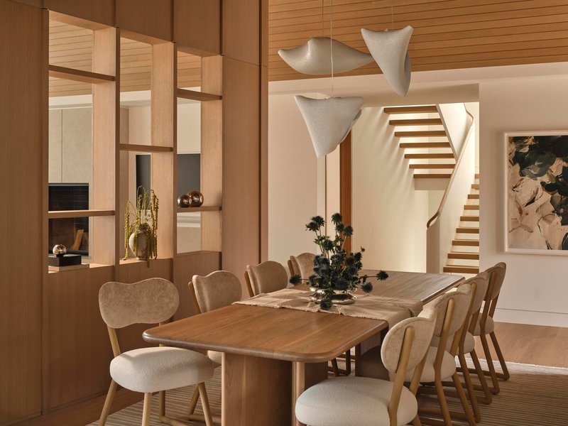 Dining area with open shelving partition and timber staircase visible in the evening light