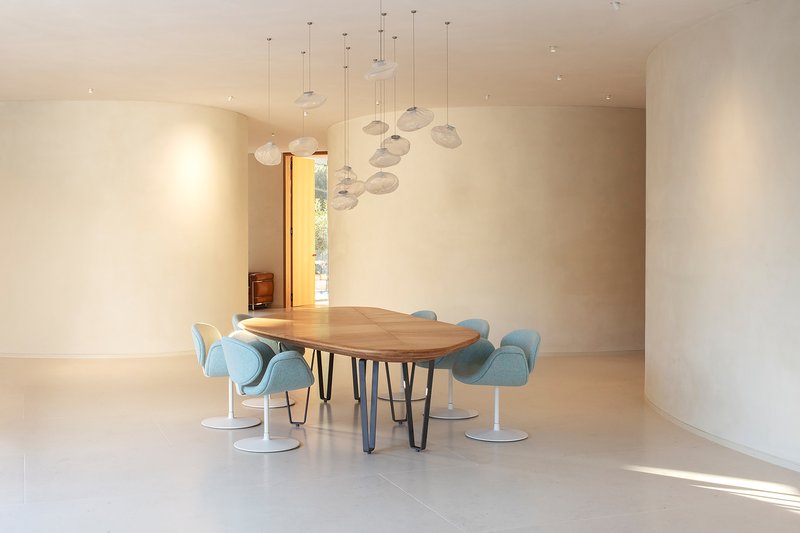 Dining space with live-edge wood table, blue swivel chairs, and cascading glass pendant lights