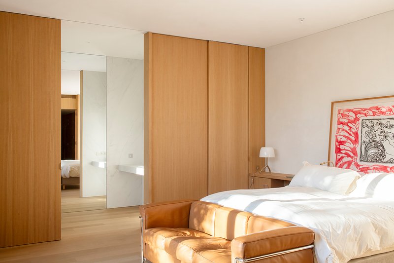 Bedroom with oak wardrobe panels, white bedding, and a framed artwork above the nightstand