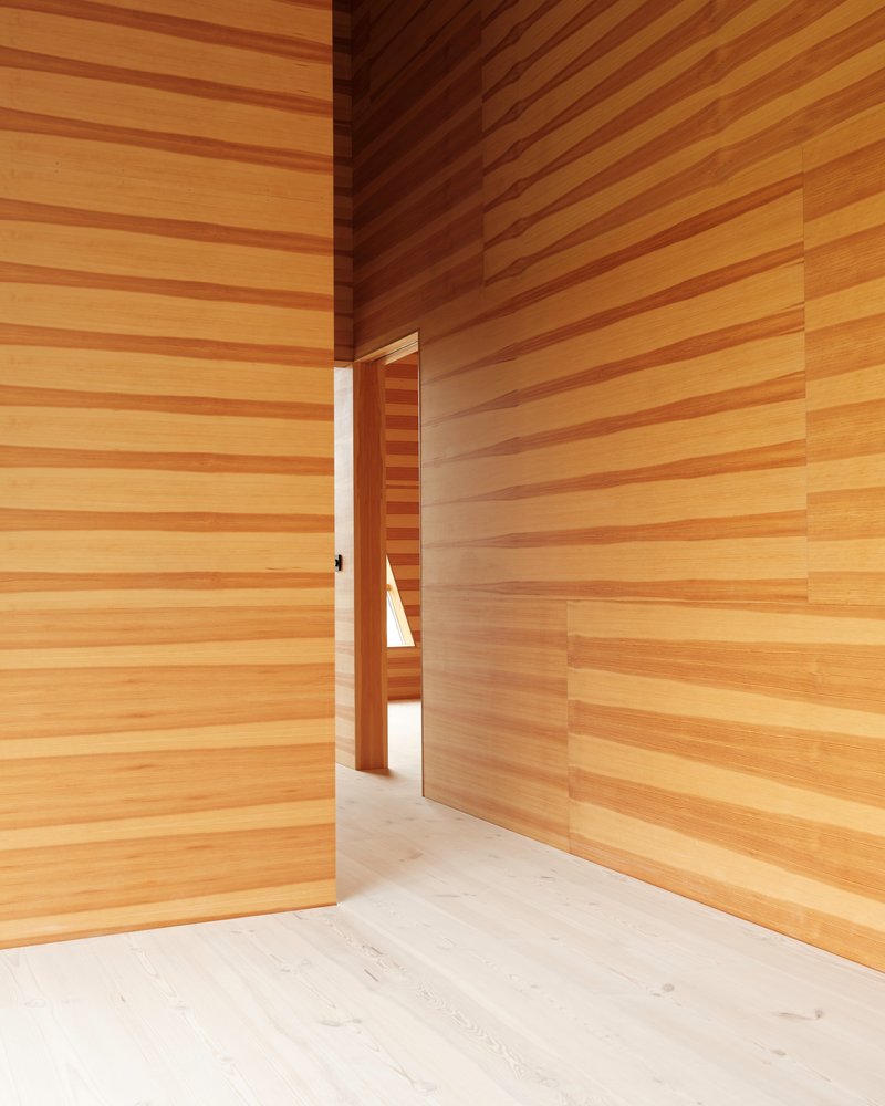 Narrow doorway framing a passage through horizontal timber clad walls in warm natural light