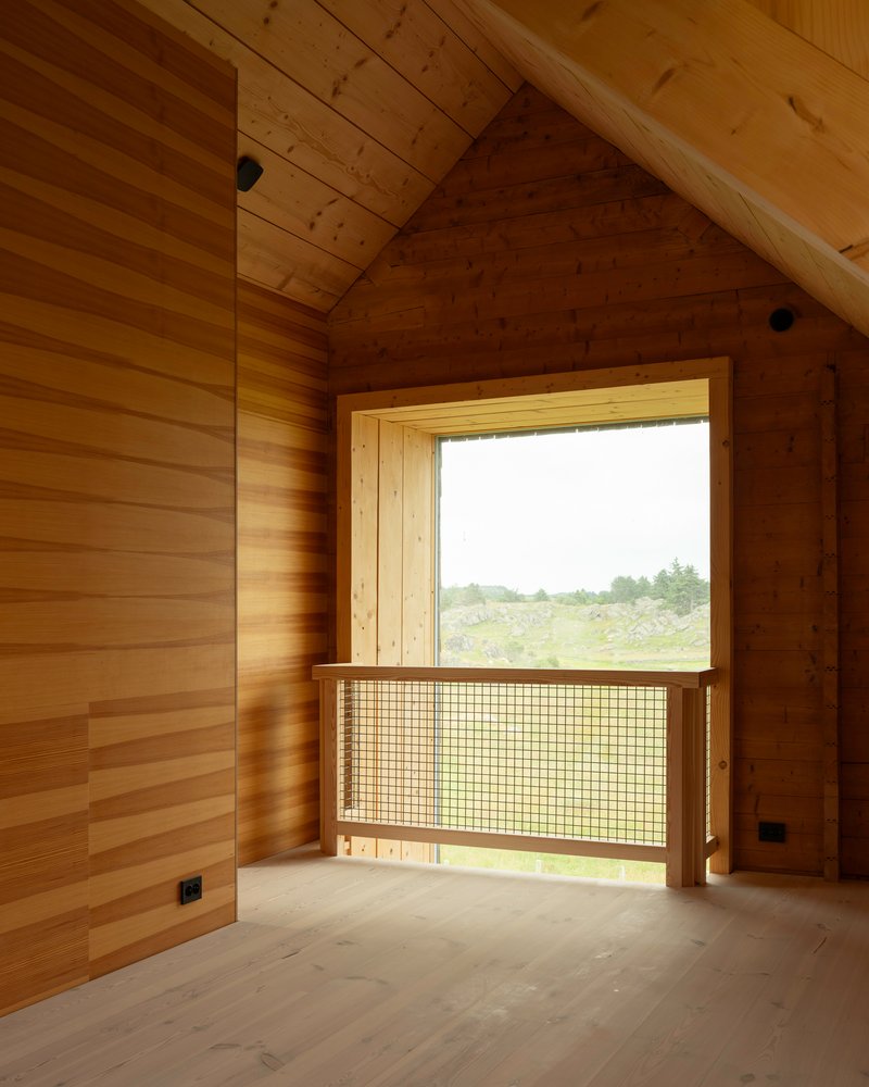 Timber-lined alcove with window featuring mesh guard rail and view to green meadow