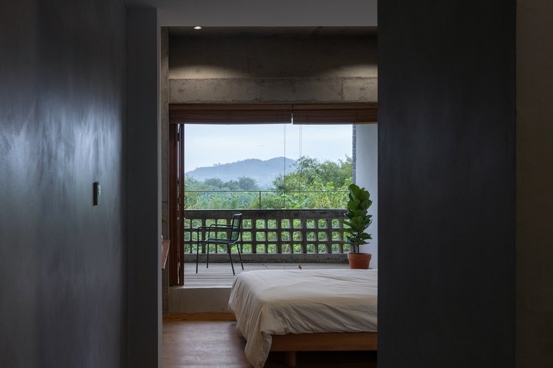 Bedroom framed by dark walls with a gridded timber balustrade opening to misty hills