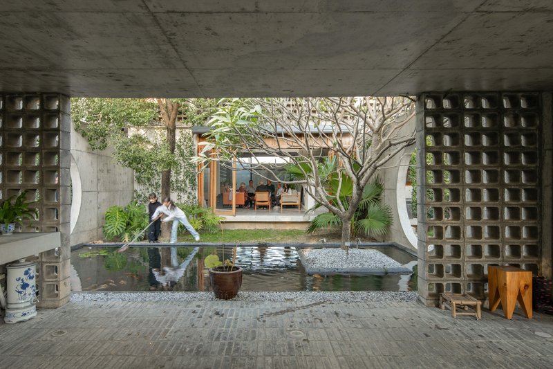 Covered terrace with reflecting pool and perforated concrete block screens overlooking a planted courtyard