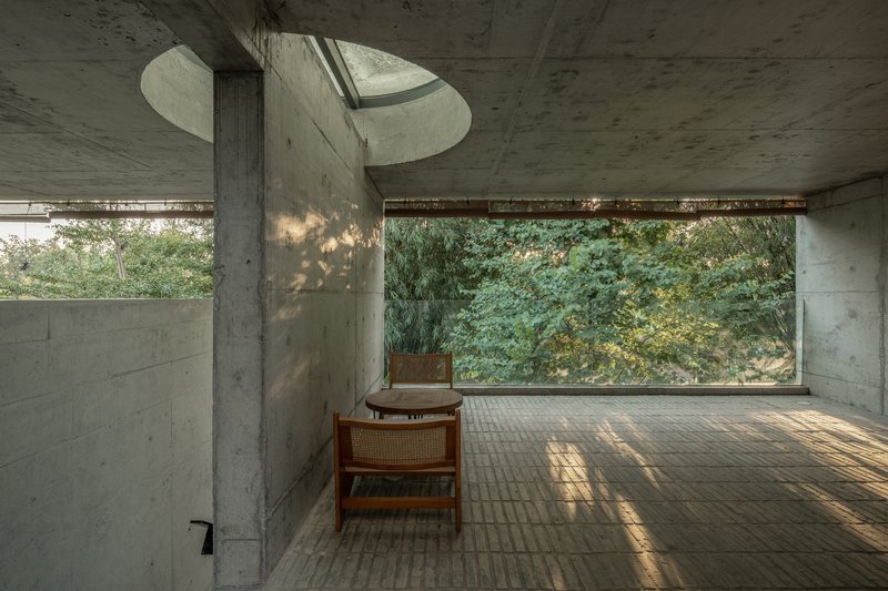 Interior room with curved concrete skylight and brick floor filtering dappled afternoon light