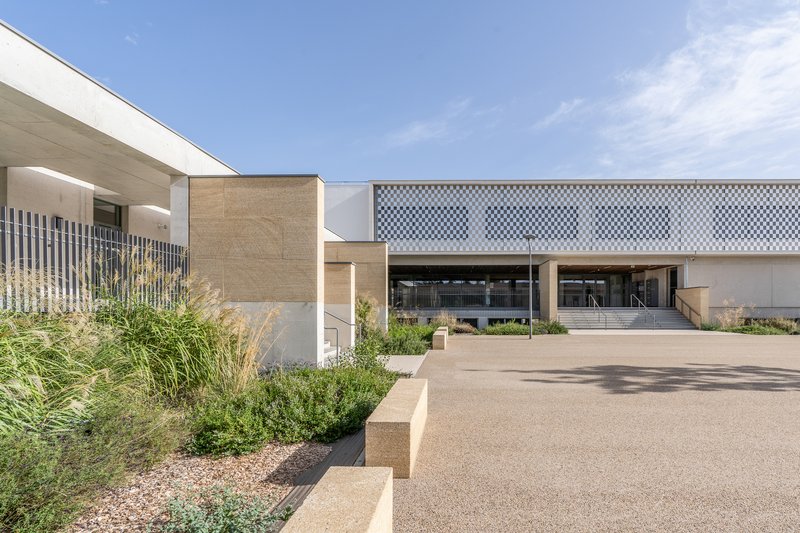 Entry drive framed by gravel beds with grasses and chequered facade screen panel