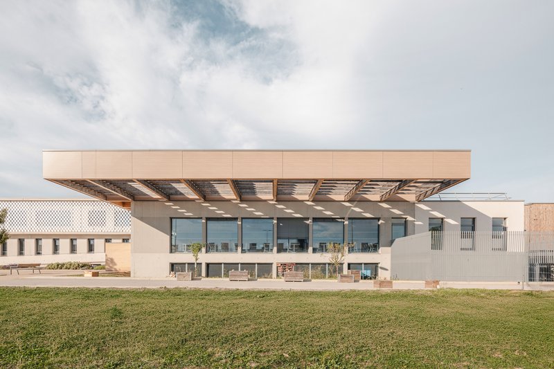 Cantilevered upper floor with exposed timber beams and full-height glazing viewed across a lawn
