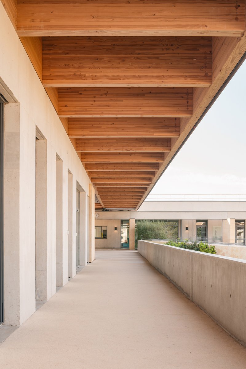 Covered walkway with exposed timber beams overhead and concrete planter along one edge
