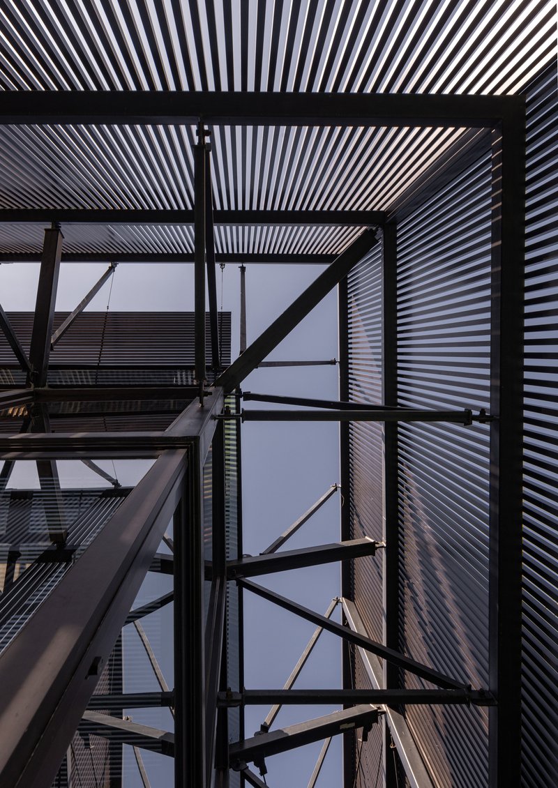 Looking up through the exposed steel frame structure with corrugated metal cladding against dusk sky