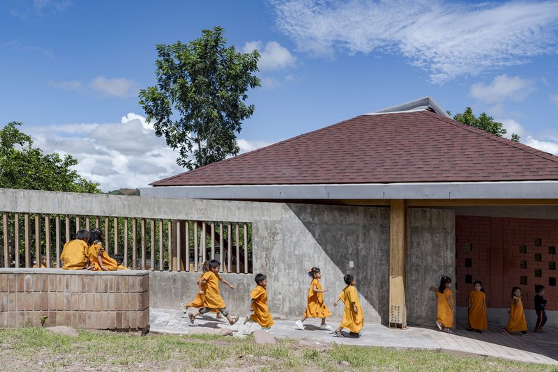 Concrete boundary wall with vertical timber slats and raised seating ledge where two figures sit under scattered clouds
