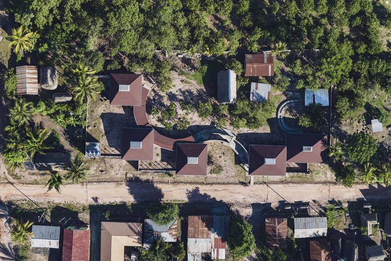 Aerial view of red tile roofs clustered among palm trees and dense tropical vegetation