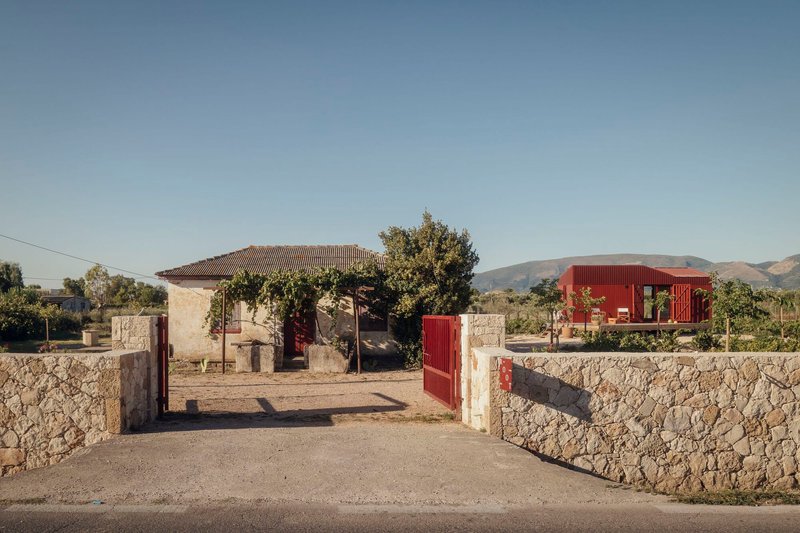 Entry gate in a low stone wall looking toward the house and an old stone outbuilding