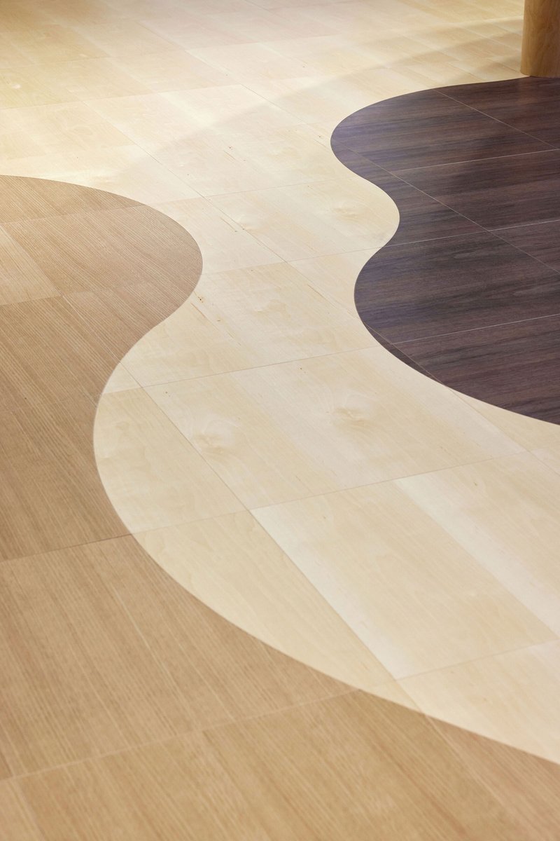 Overhead view of curved flooring patterns in light and dark wood meeting at organic boundaries