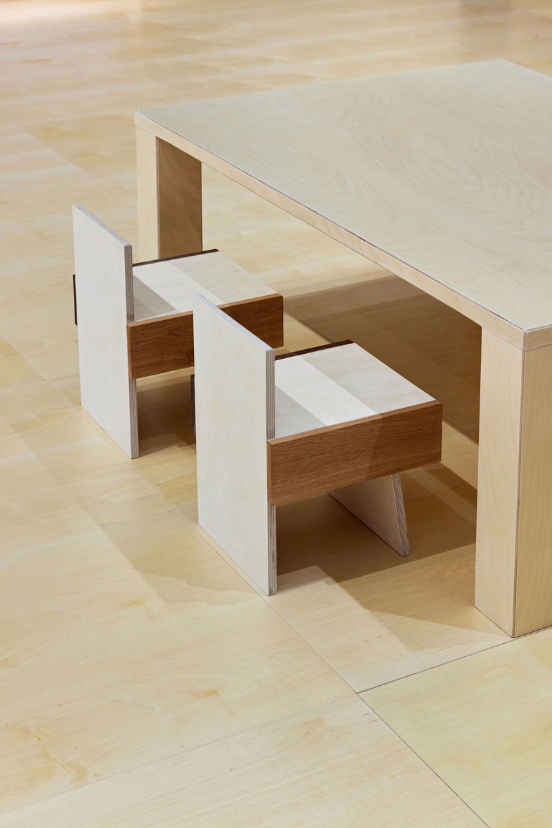Physical model showing a table with integrated stepped seating units cut into the plywood base