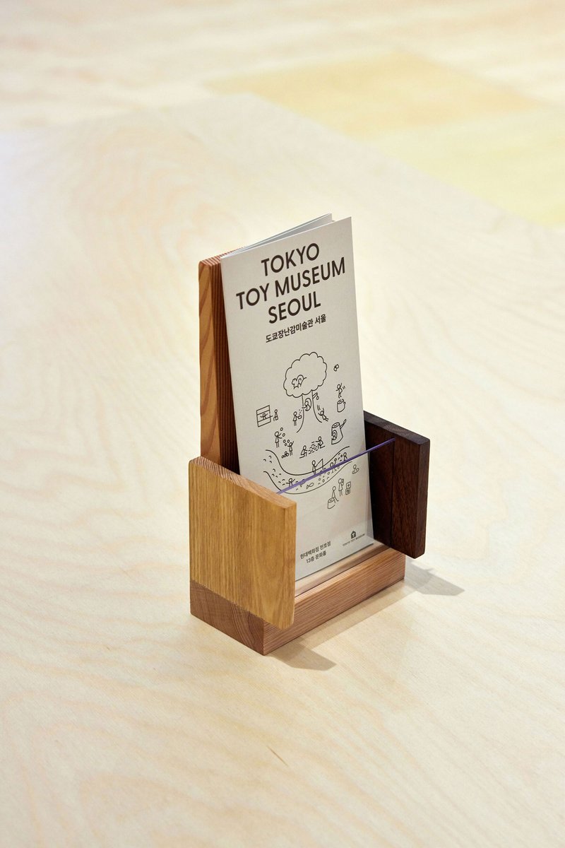 Wooden brochure holder displaying a printed card on a light-colored surface with soft shadows
