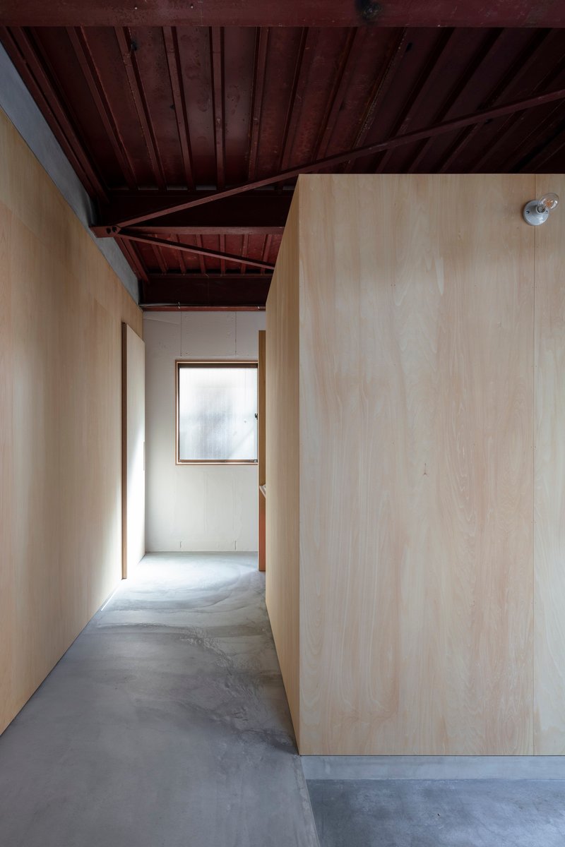 Hallway with exposed reddish-brown timber roof beams and polished concrete floor