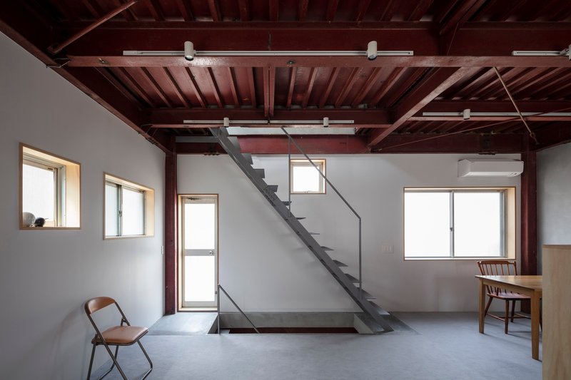 Room with diagonal steel stair crossing beneath exposed timber joists and track lighting