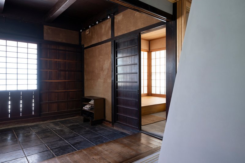Entrance vestibule with dark stone tile floor and sliding timber door opening to tatami room with paper screens