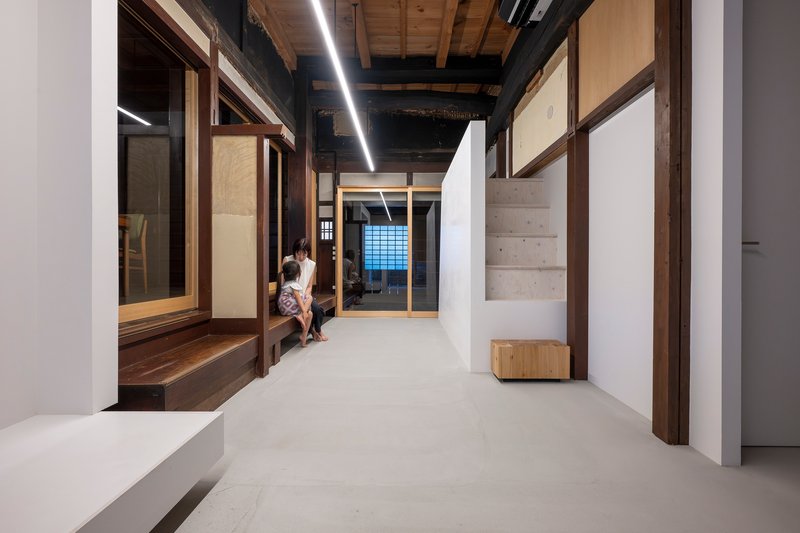 Hallway with two people sitting on timber bench beneath continuous linear ceiling fixture