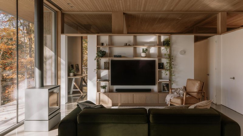 Living room with built-in shelving unit beneath exposed timber ceiling and full-height windows