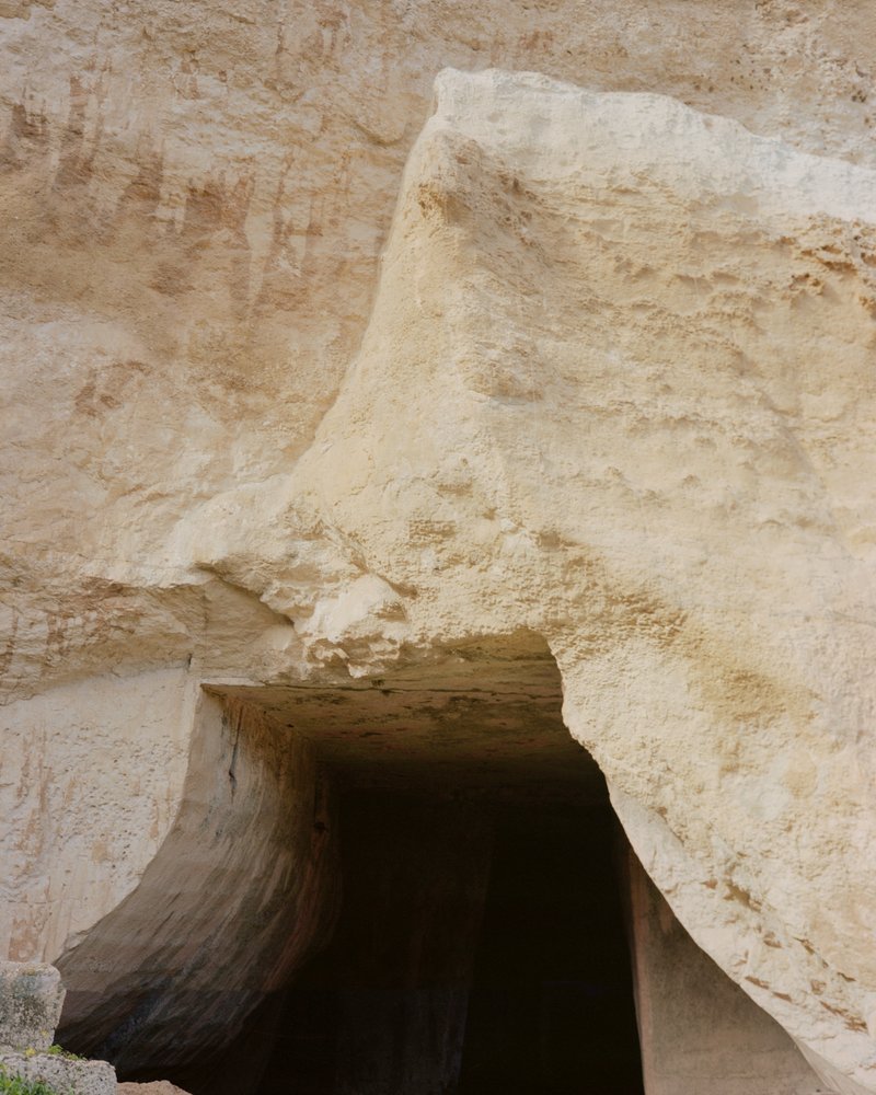 Carved sandstone archway opening into a shadowed interior passage with weathered walls