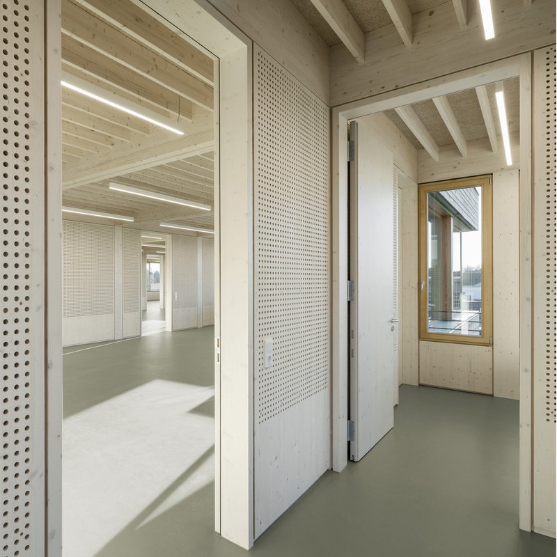 Interior threshold showing perforated white panel door between timber-framed spaces with resin flooring