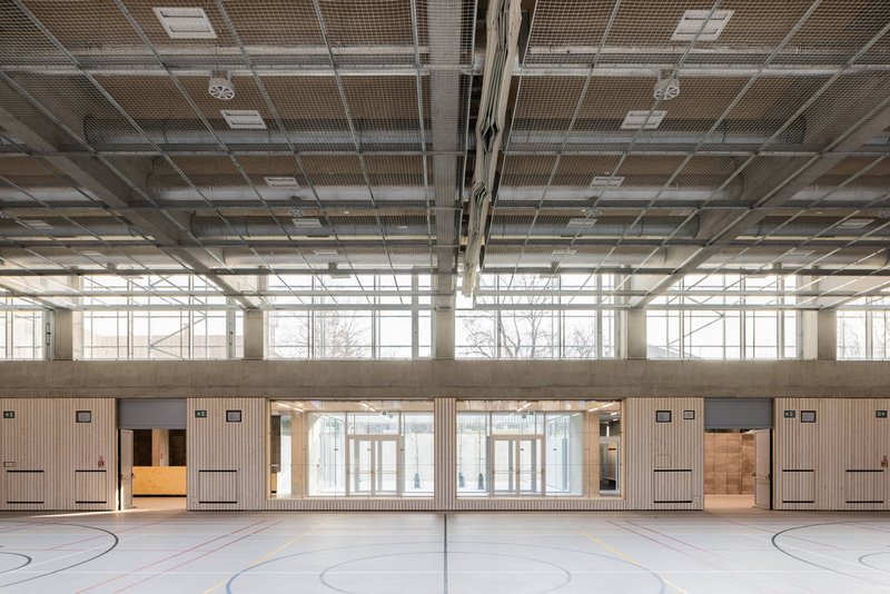 View across the gymnasium showing clerestory windows and timber wall cladding beneath the exposed ceiling structure