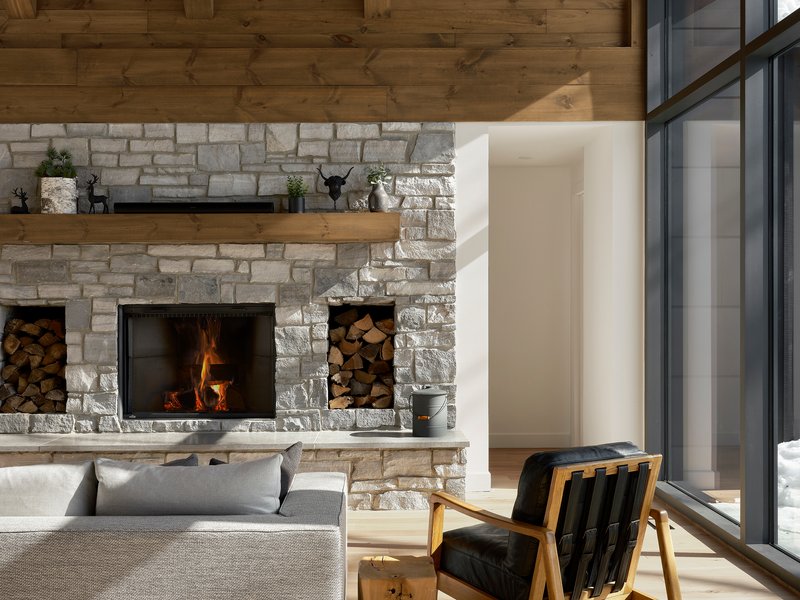 Stacked stone fireplace wall with timber mantel and built in wood storage niches flanking hearth