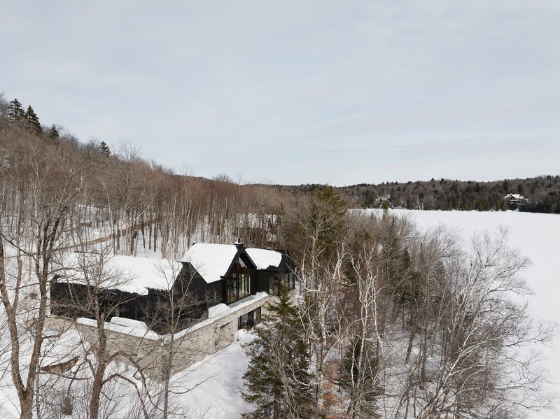 Distant view of the stone and timber residence on a hillside among bare and evergreen trees