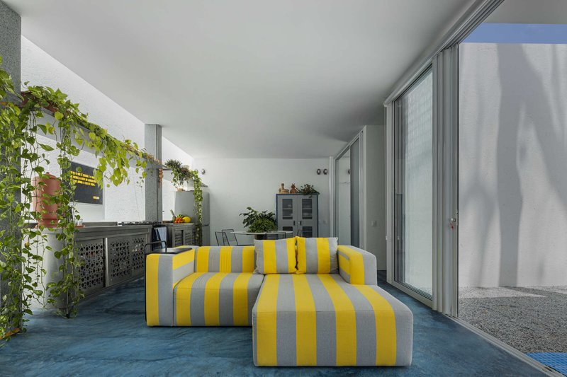 Covered terrace with blue floor, yellow and grey striped seating and sliding glass doors