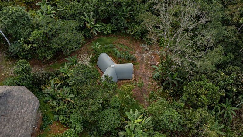 Aerial view of the grey vaulted roof nestled into a clearing surrounded by tropical vegetation