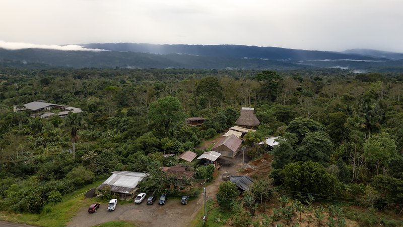 Drone view of the compound with vaulted roofs emerging from dense rainforest at dusk
