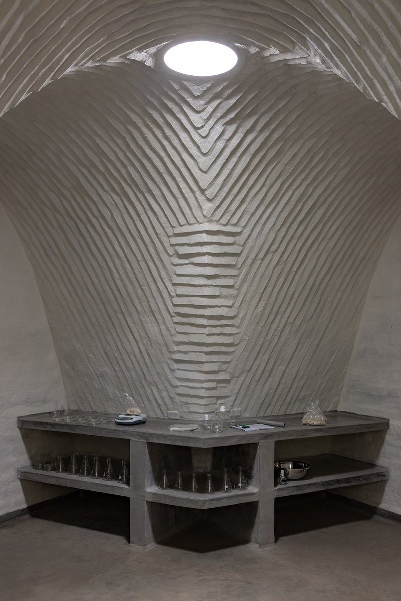 Vaulted space with circular skylight above stepped concrete counters and glassware